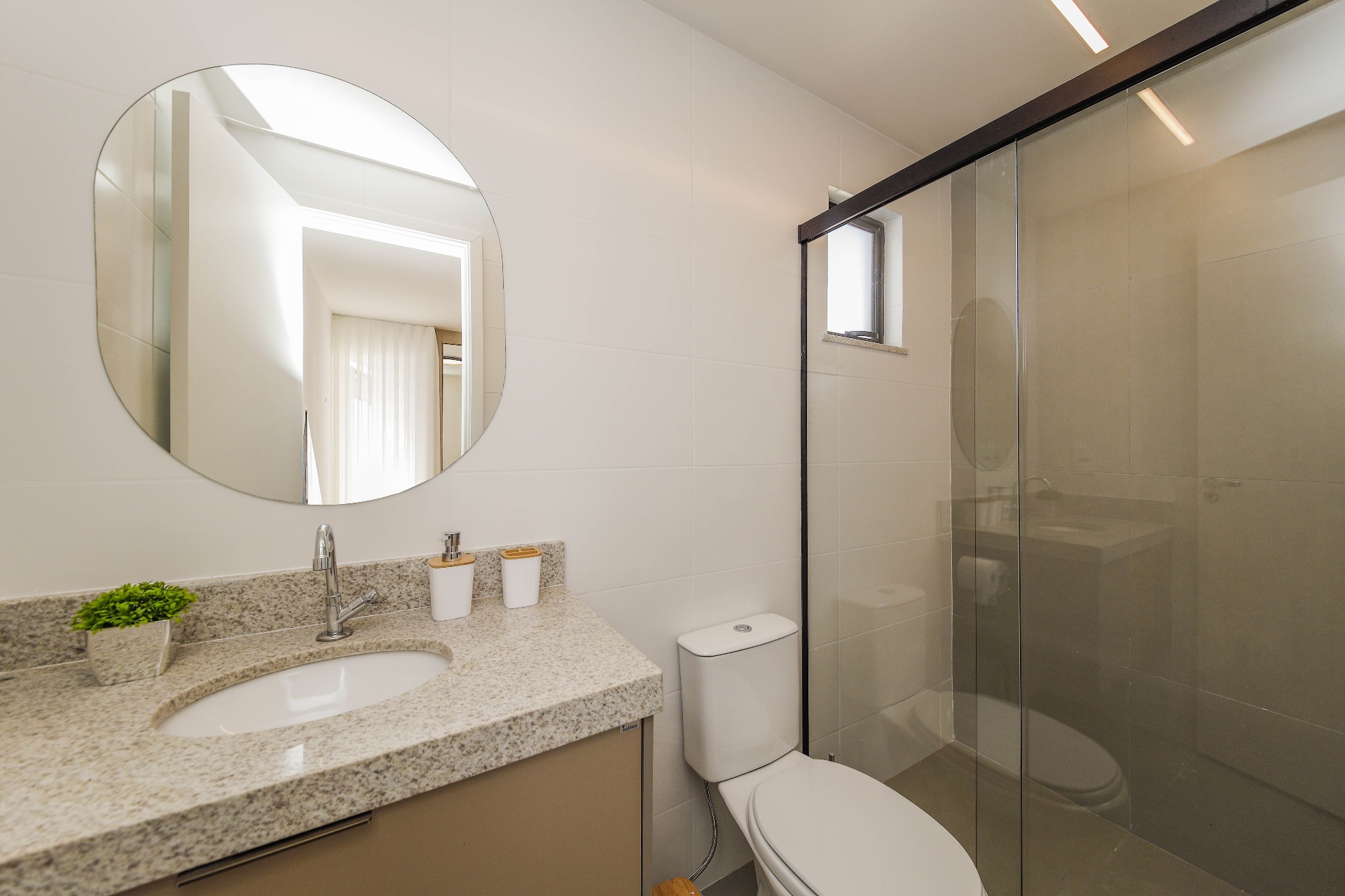 Banheiro do decorado com bancada em granito, box e espelho redondo