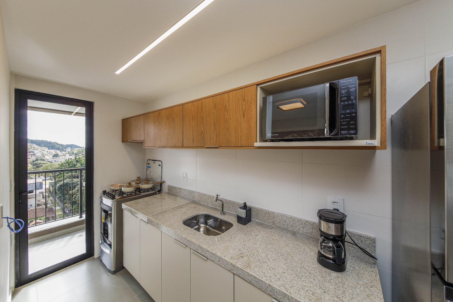 Cozinha do decorado com fogão, bancada em granito e iluminação linear